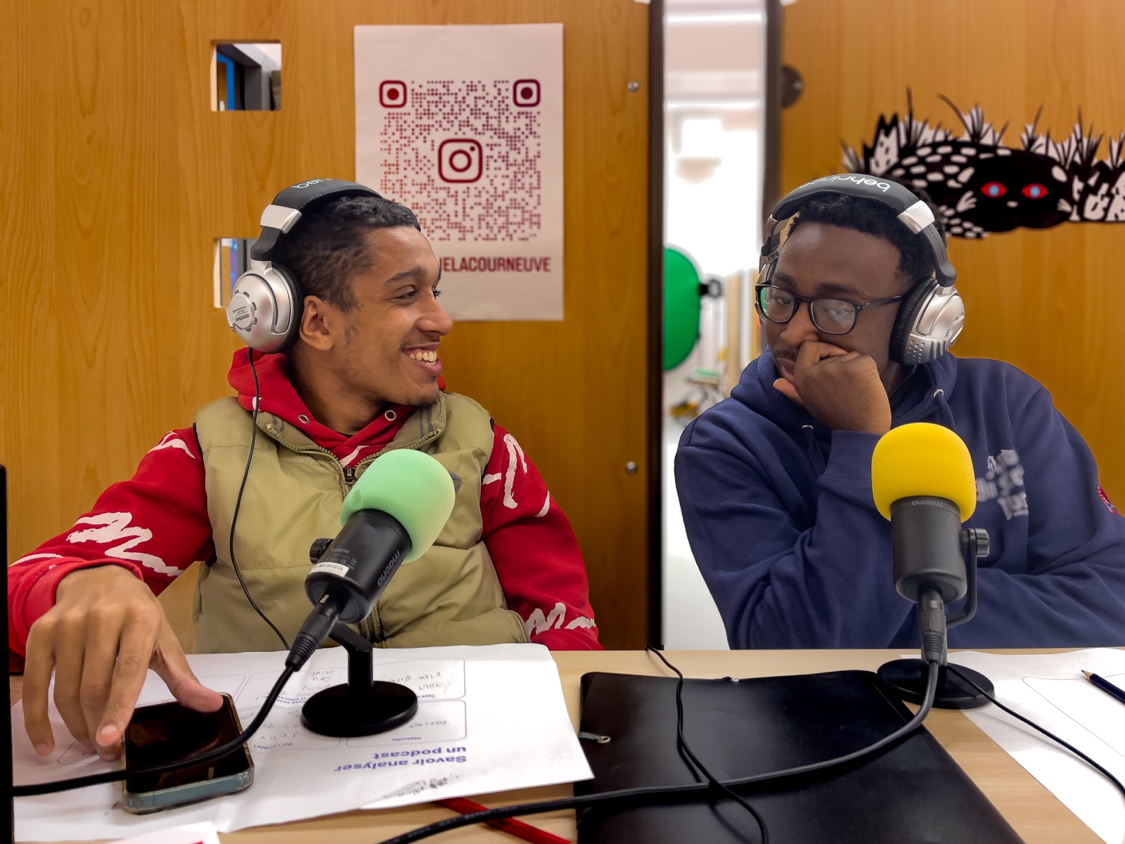 Deux participants avec des casques enregistrent un podcast devant des micros.
